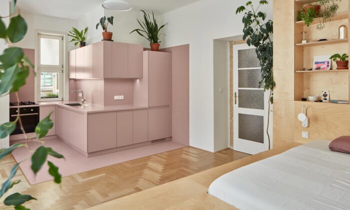 Žižkovský byt má po rekonstrukci růžovou kuchyni a multifunkční dřevěné pódium